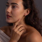 Woman with long wavy hair wearing the Art Deco Diamond Earrings & Ring Set, touching her face and looking to the side—radiating vintage glamour.