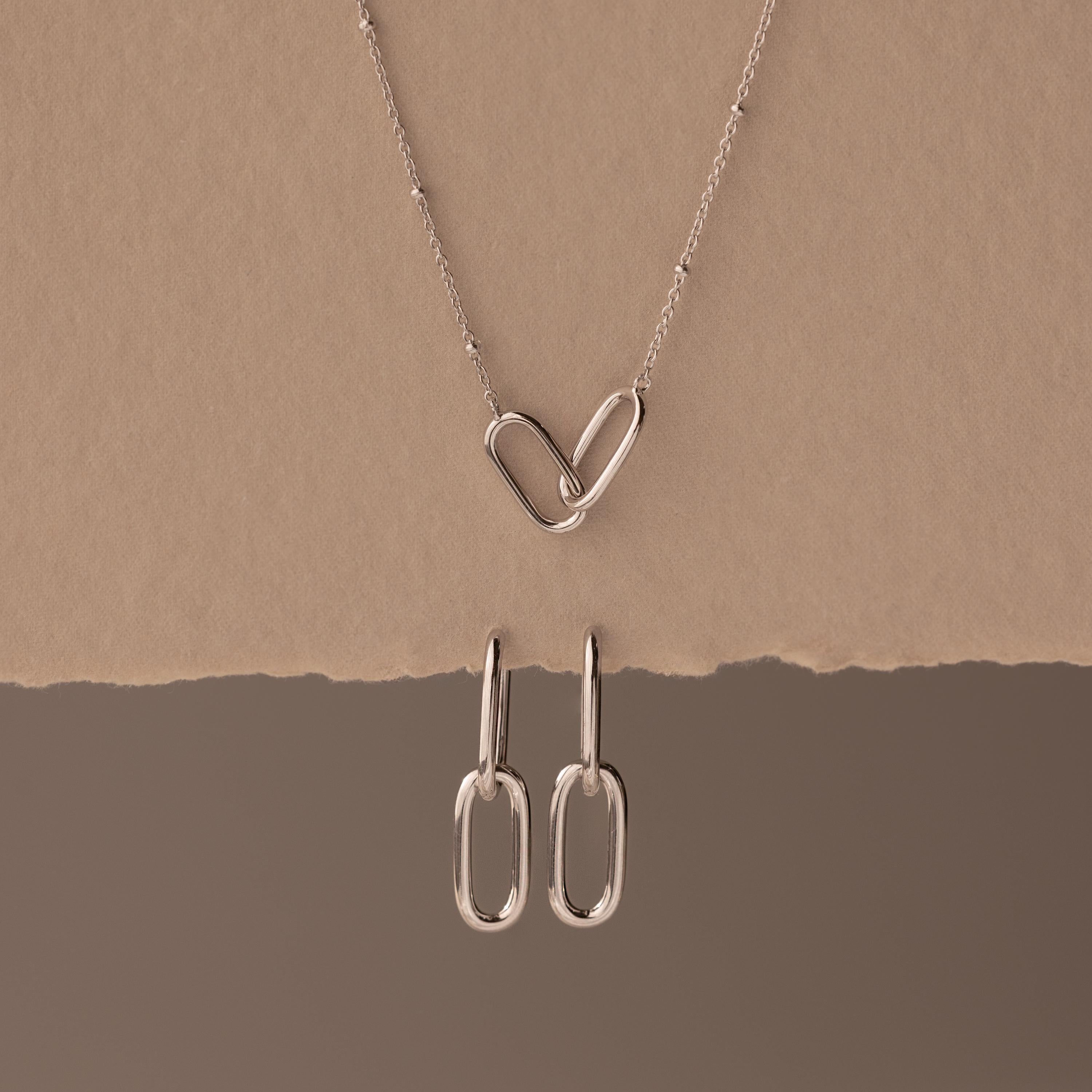 Linked Charm Necklace and Earrings Set in Sterling Silver, featuring interlocking hearts and oval links, shown on a beige background—an ideal anniversary gift.