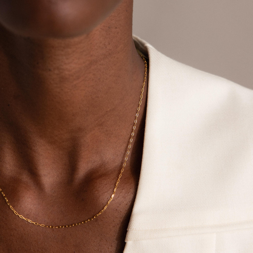 Close-up of the Dainty Paperclip Necklace in gold, worn over a white collared shirt—ideal for layering with other delicate necklaces.