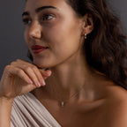 Woman with wavy dark hair wears the Diamond Butterfly Drop Jewelry Set and an off-shoulder white top, gazing thoughtfully to the side.
