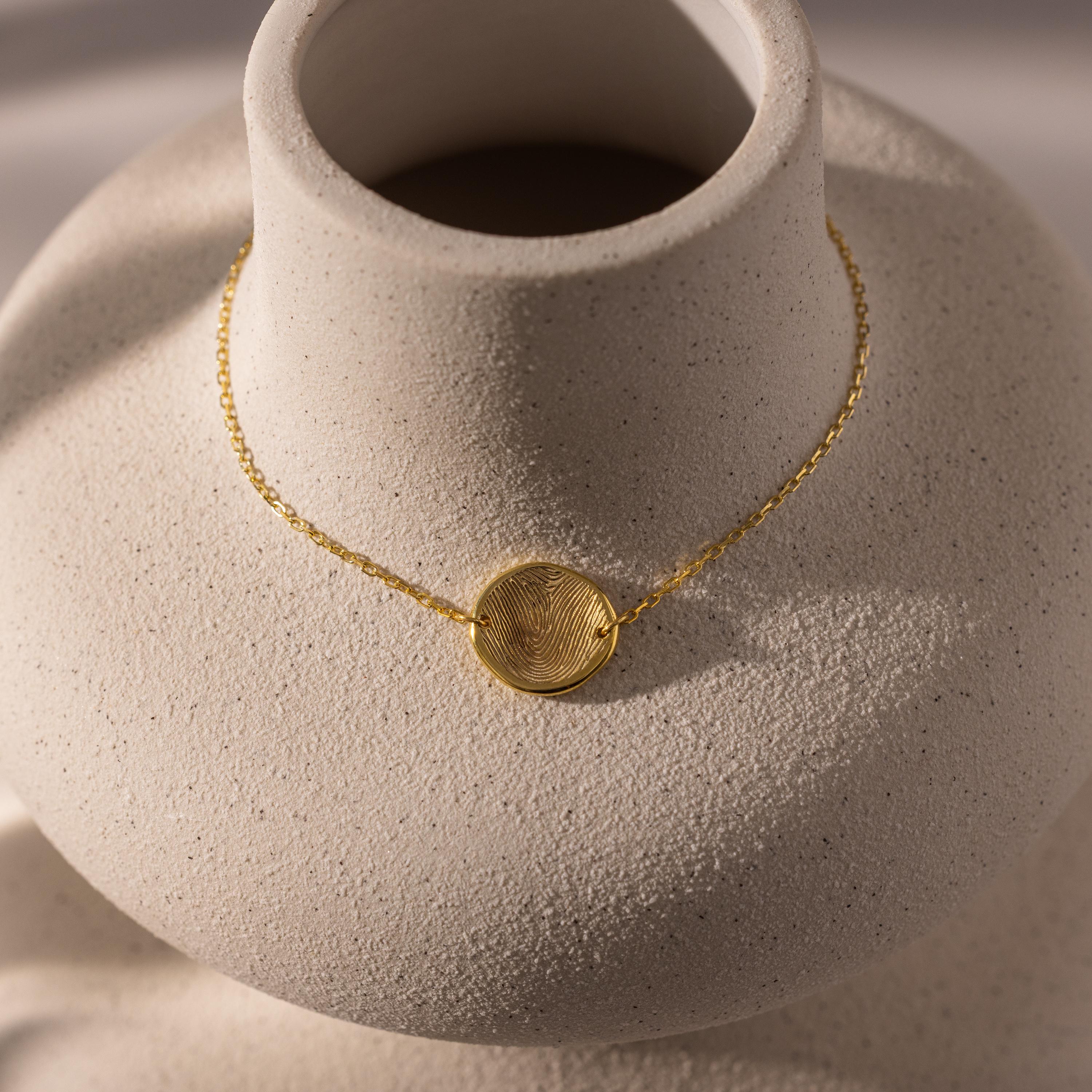 Dainty Organic Fingerprint Bracelet in 18K Gold displayed on a textured, light-colored ceramic bust—an elegant piece of personalized jewelry, perfect as a sentimental memorial gift.