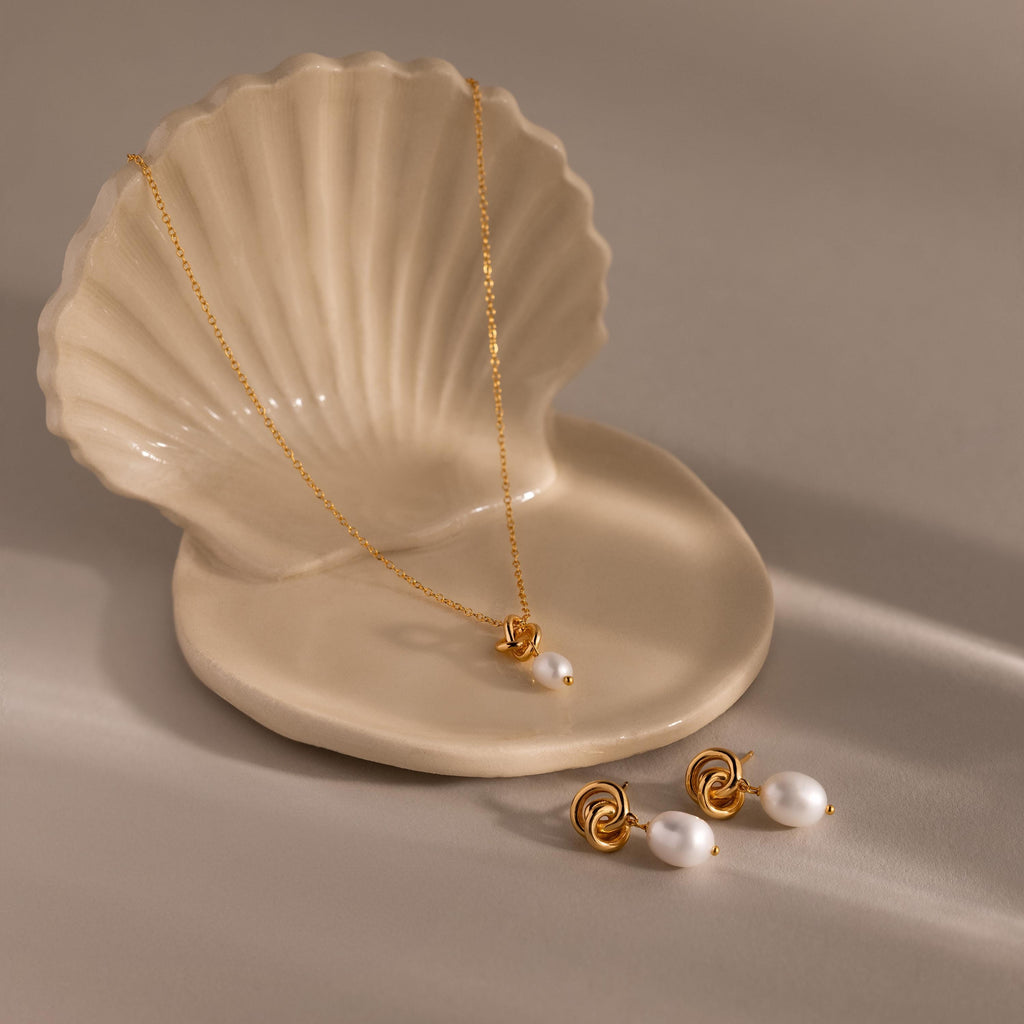 Pearl Knot Necklace & Earrings Set in 18K Gold displayed on a ceramic shell-shaped dish—an elegant gift for your wife.