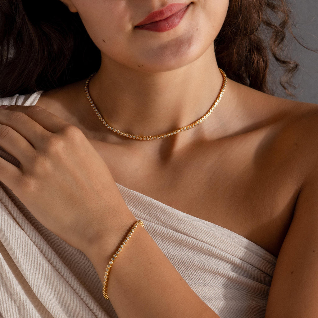 A woman wearing a Diamond Bezel Tennis Necklace & Bracelet Set, dressed in a cream-colored, off-shoulder top.