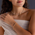 A woman smiles softly in a light off-shoulder top, wearing the 3-Prong Diamond Tennis Necklace & Bracelet Set in 18K Gold.