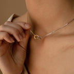 Close-up of a person holding a gold and silver Interlocking Circles Necklace from the Interlocking Circles Necklace and Bracelet Set near their neck.