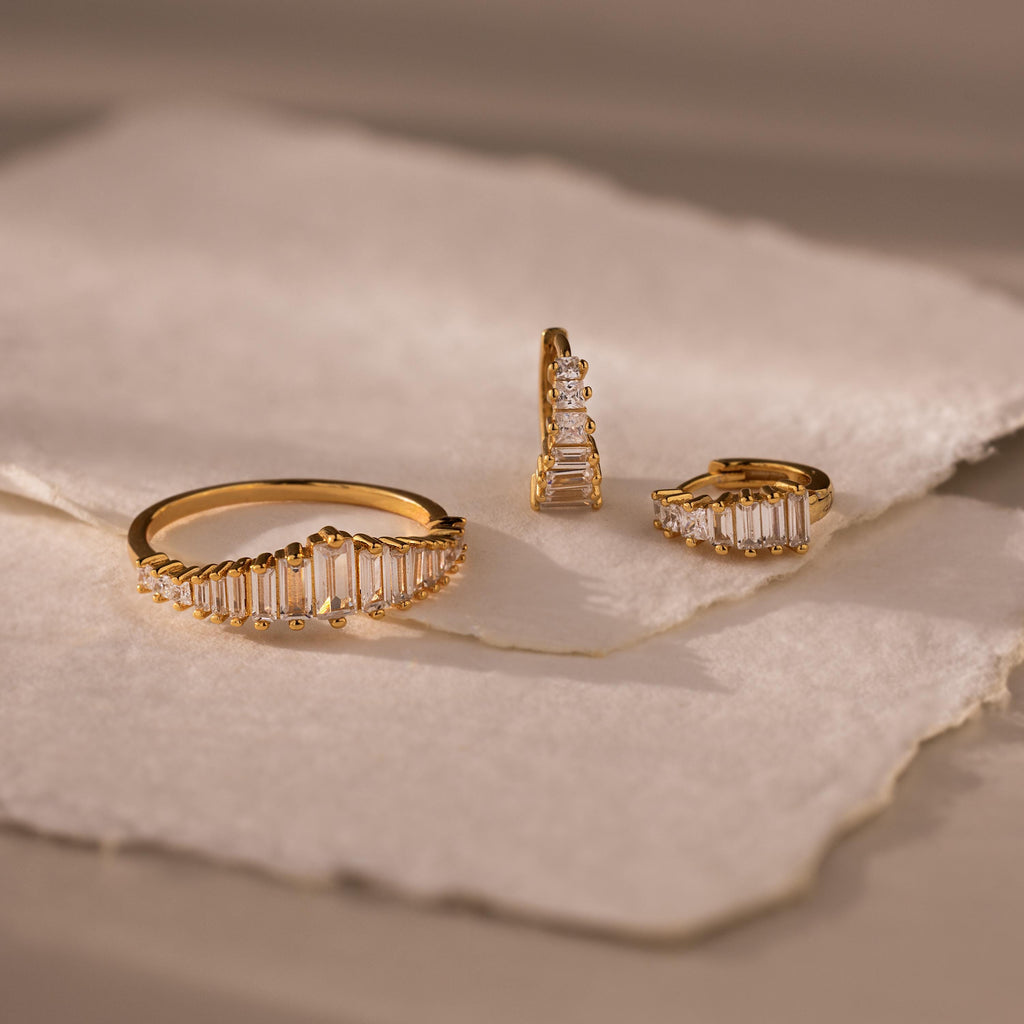 Art Deco Diamond Earrings & Ring Set, featuring a gold ring and two gold earrings with small diamonds, evocative of vintage glamour, displayed on textured white paper.