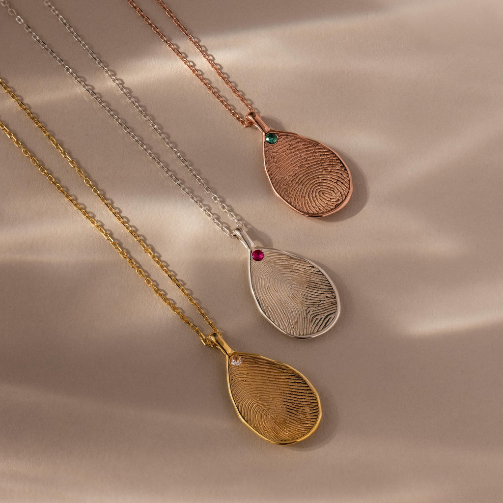 The Fingerprint Birthstone Teardrop Necklace, available in gold, silver, and rose gold, features delicate gemstone accents—personalized jewelry that uniquely captures your story.