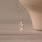 The Fingerprint Birthstone Teardrop Necklace features a teardrop silver pendant with your fingerprint and a red birthstone on a delicate chain—a personalized jewelry piece for meaningful style.