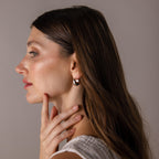 Woman with long brown hair wears a white top and Bold Teardrop Earrings in White Gold, touching her chin in side profile.