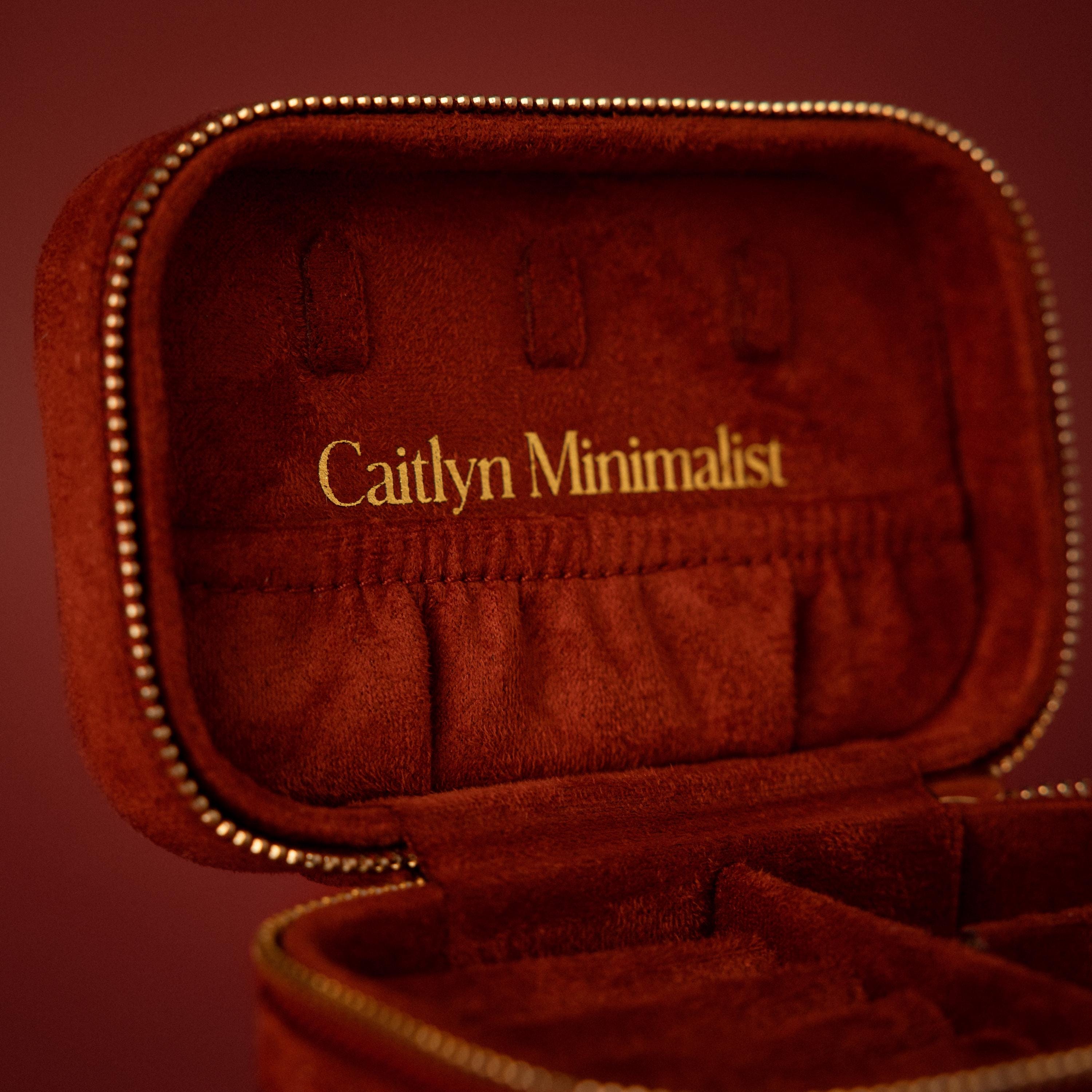 A cherry red velvet jewelry case with Caitlyn Minimalist embroidered in gold inside the lid, perfect for luxury jewelry storage and organizing your cherished pieces.
