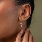 Close-up of a model wearing our Teardrop Ribbon Charm Hoops in gold 