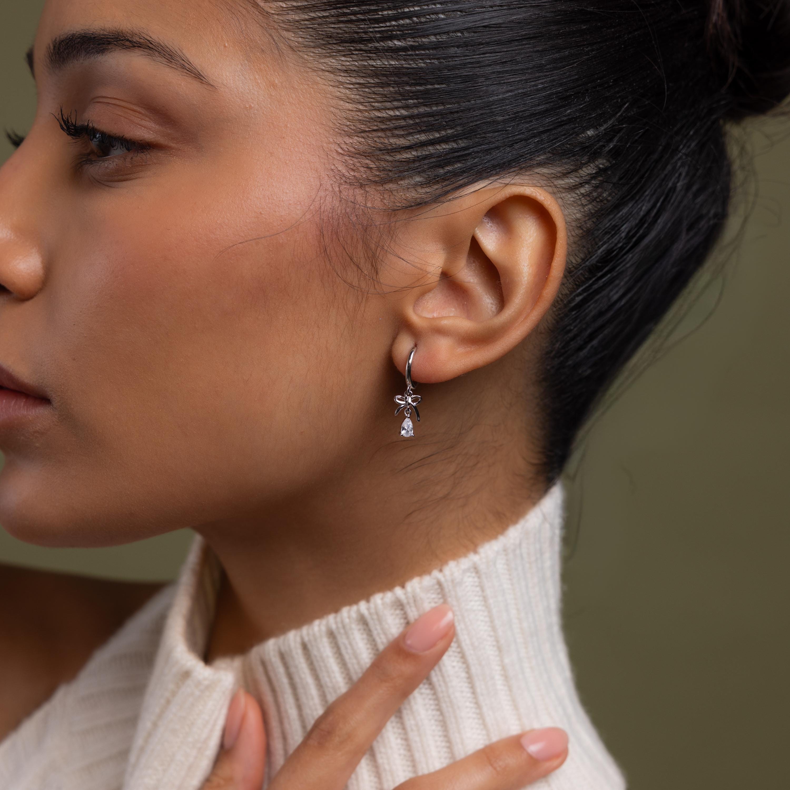 Close-up of a model wearing our Teardrop Ribbon Charm Hoops in Silver