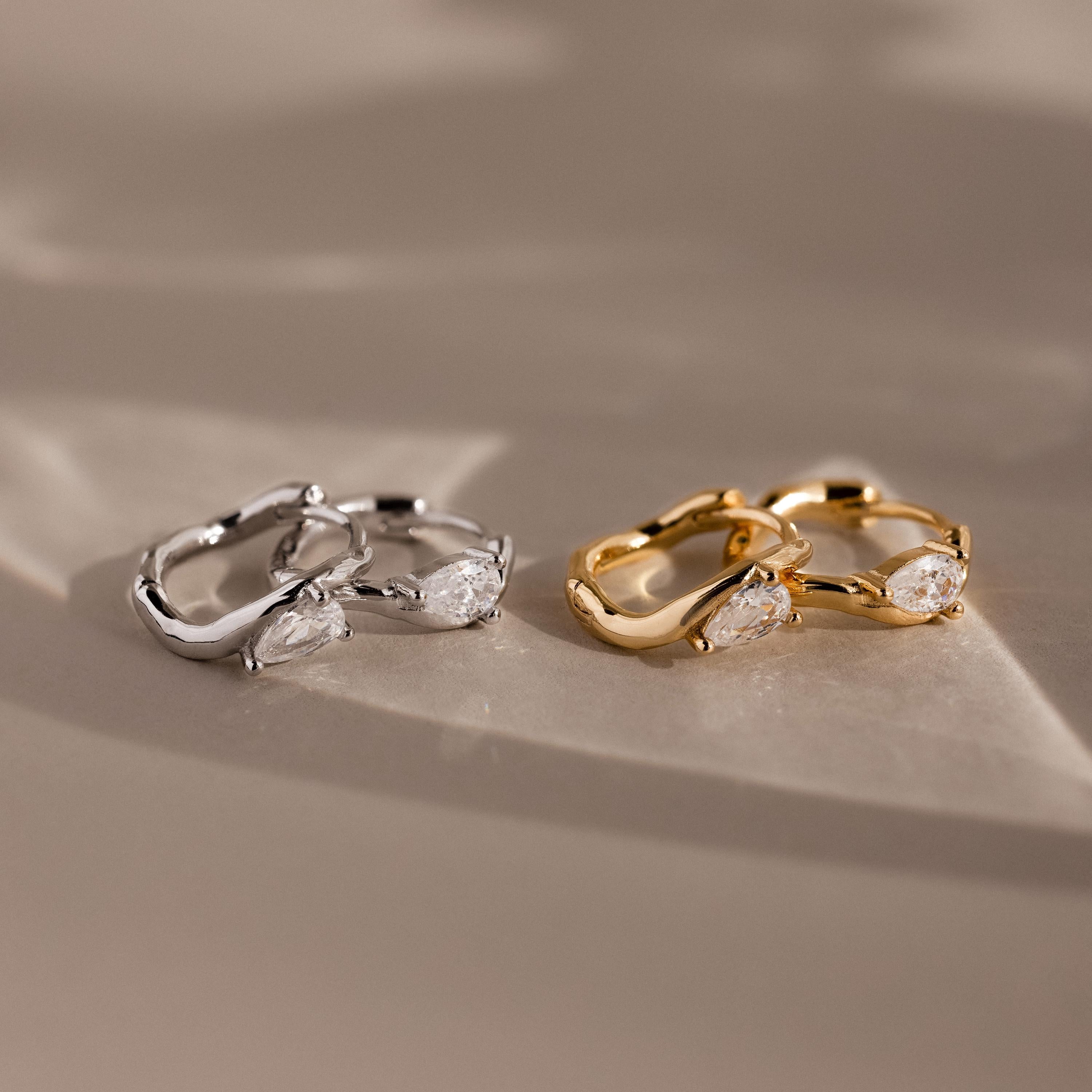 Flatlay of 2 pairs of our Hammered Diamond Teardrop Hoops in Silver and Gold