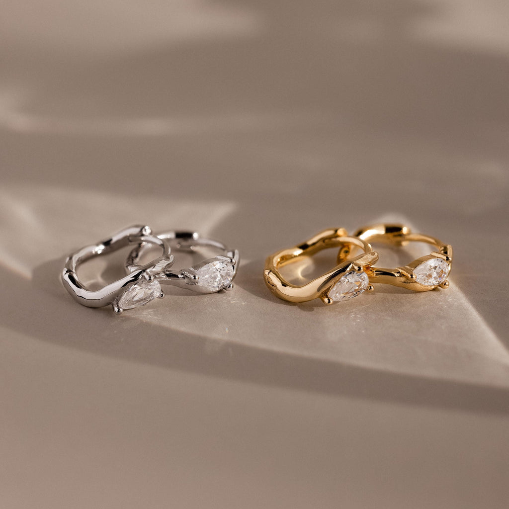 Flatlay of 2 pairs of our Hammered Diamond Teardrop Hoops in Silver and Gold