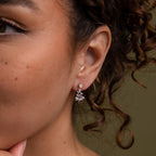 Close-up of a model wearing our Holiday Diamond Tree Studs in Silver with a green background