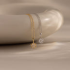 Gold and silver necklaces with poinsetta pendants on a beige background