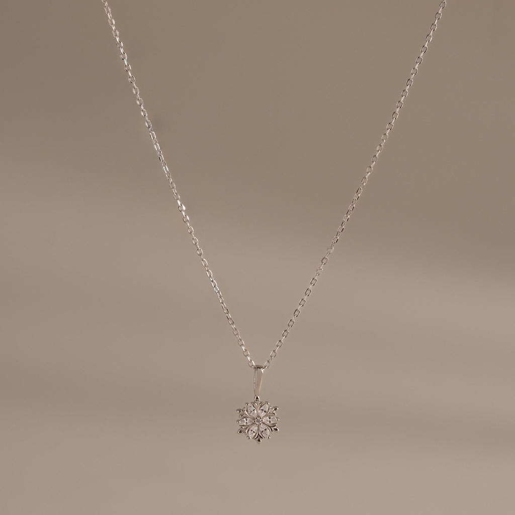 Flat;ay of our Diamond Poinsettia Necklace in Silver on a beige background
