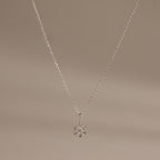 Flat;ay of our Diamond Poinsettia Necklace in Silver on a beige background