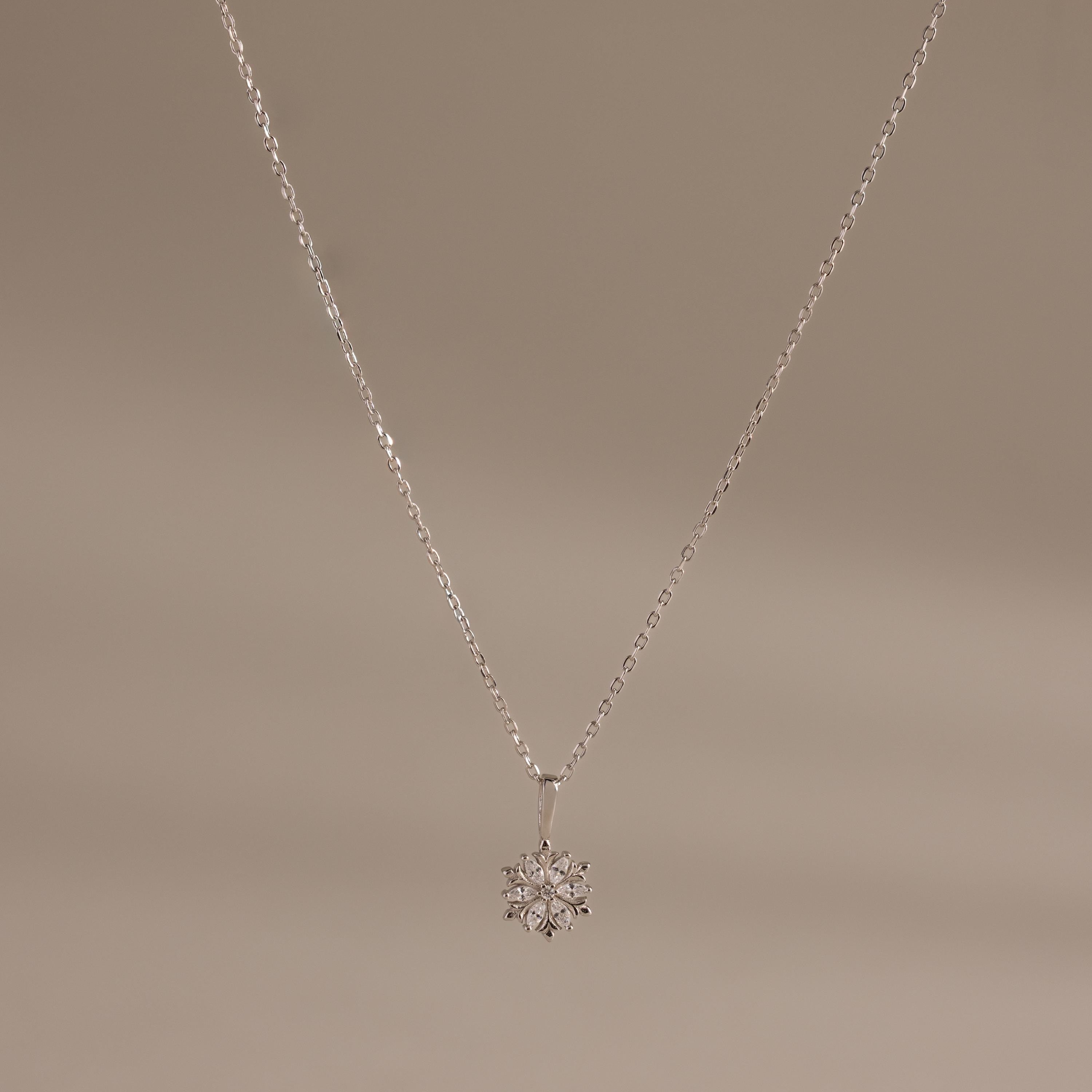 Flat;ay of our Diamond Poinsettia Necklace in Silver on a beige background