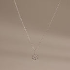 Flatlay of our Diamond Poinsetta Pendant Necklace in Silver