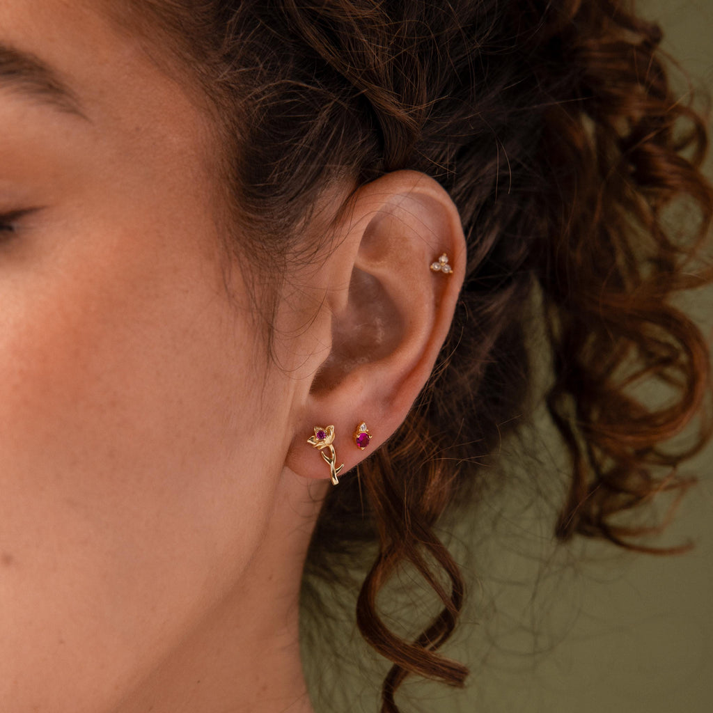 Close-up of a model wearing our Birth Flower Stud Earrings, styled with out cluster earrings and Ruby birthstone stud earrings