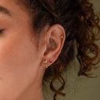 Close-up of a model wearing our Birth Flower Stud Earrings, styled with out cluster earrings and Ruby birthstone stud earrings
