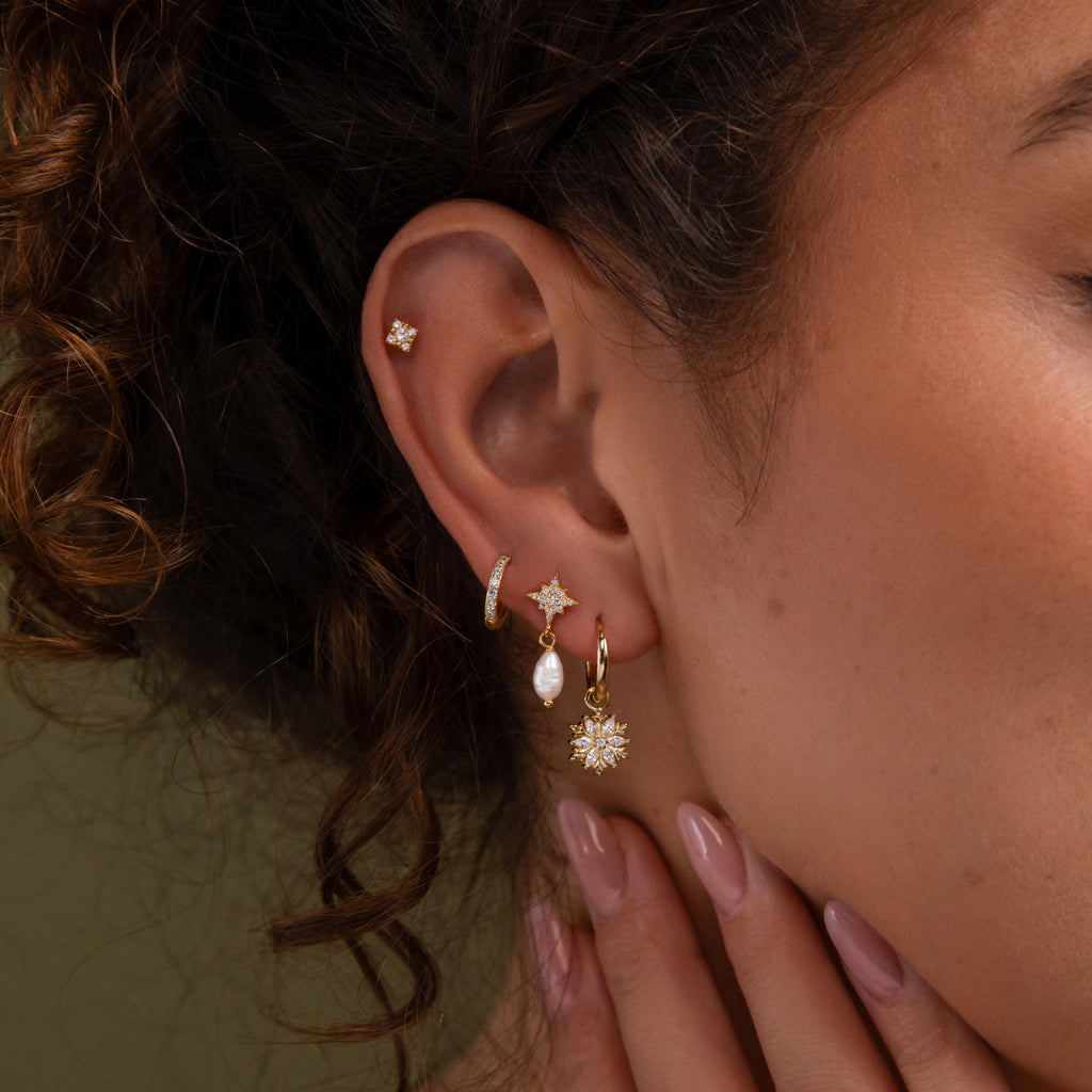 Close-up of a model wearing our Diamond Poinsettia Hoops, styled with our Diamond Daydreamer Studs, Coco Pave Hoops and Moon & Star Pearl Earrings