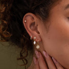Close-up of a model wearing our Diamond Poinsettia Hoops, styled with our Diamond Daydreamer Studs, Coco Pave Hoops and Moon & Star Pearl Earrings