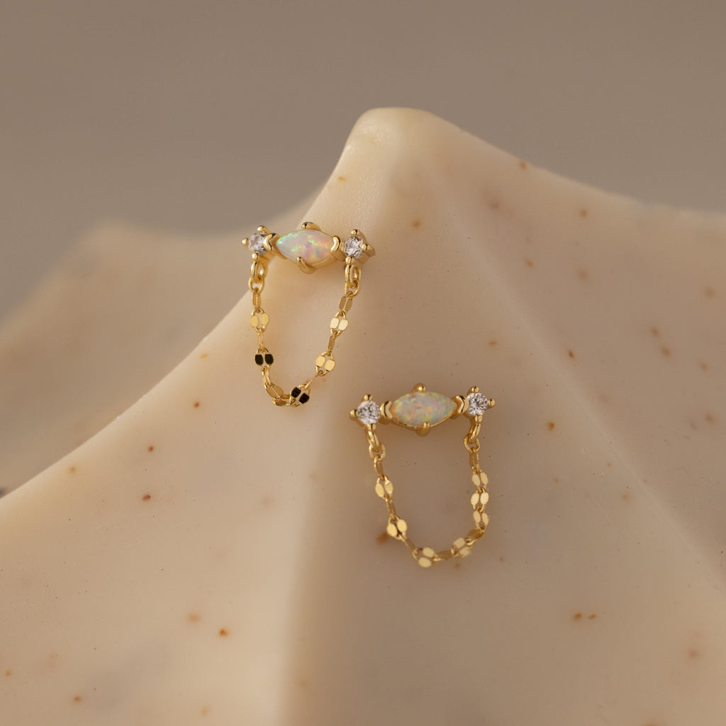 Flatlay of our Opal & Diamond Chain Studs on a beige surface