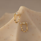 Flatlay of our Opal & Diamond Chain Studs on a beige surface