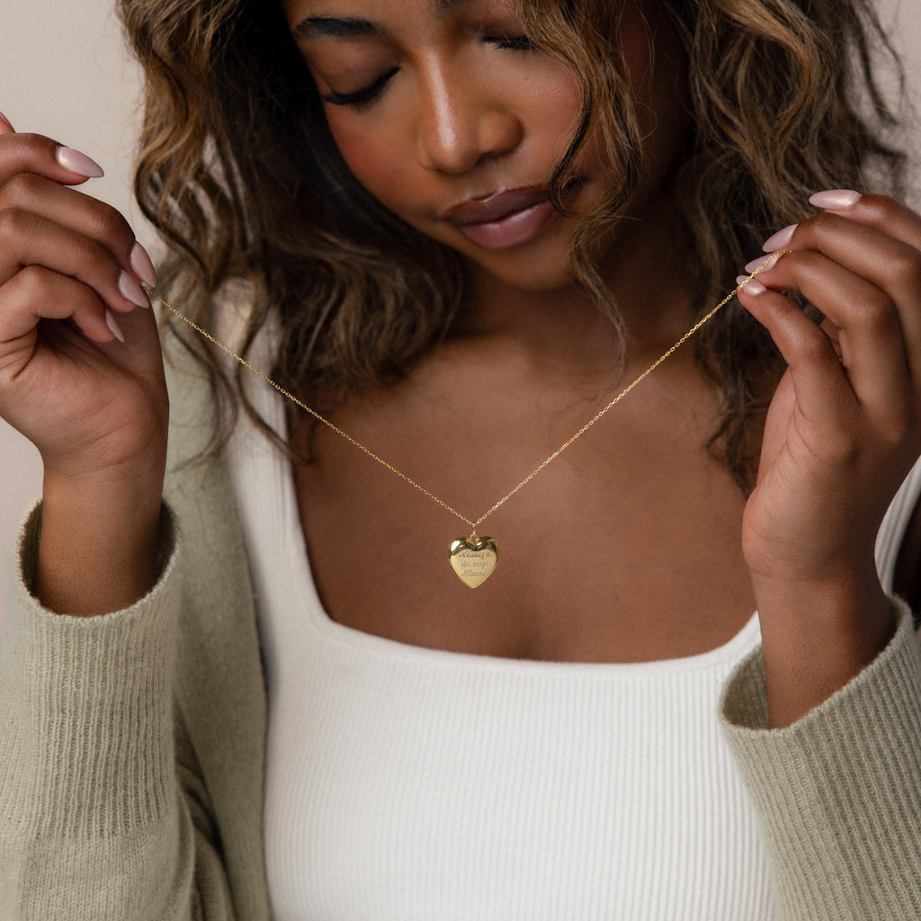 Image of model holding our Engraved Heart Locket Necklace in 18K Gold