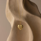 Flatlay of our Engraved Heart Locket Necklace in 18K Gold