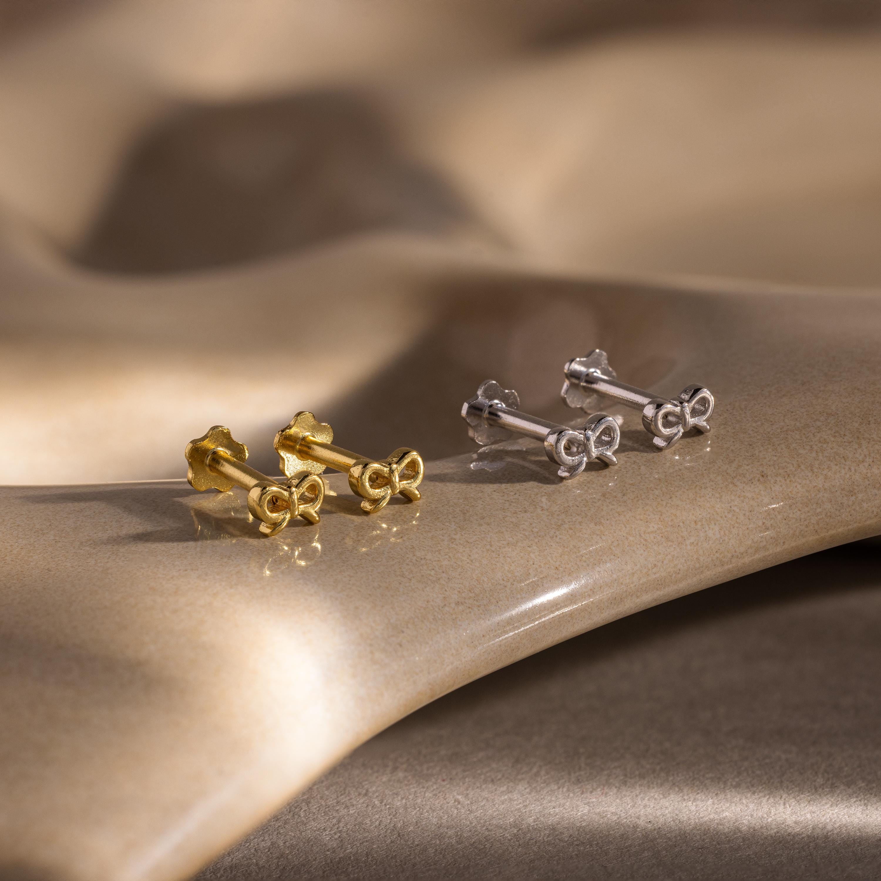 Flatlay of 2 pairs of our Tiny Bow Flatback Studs in Gold and Silver