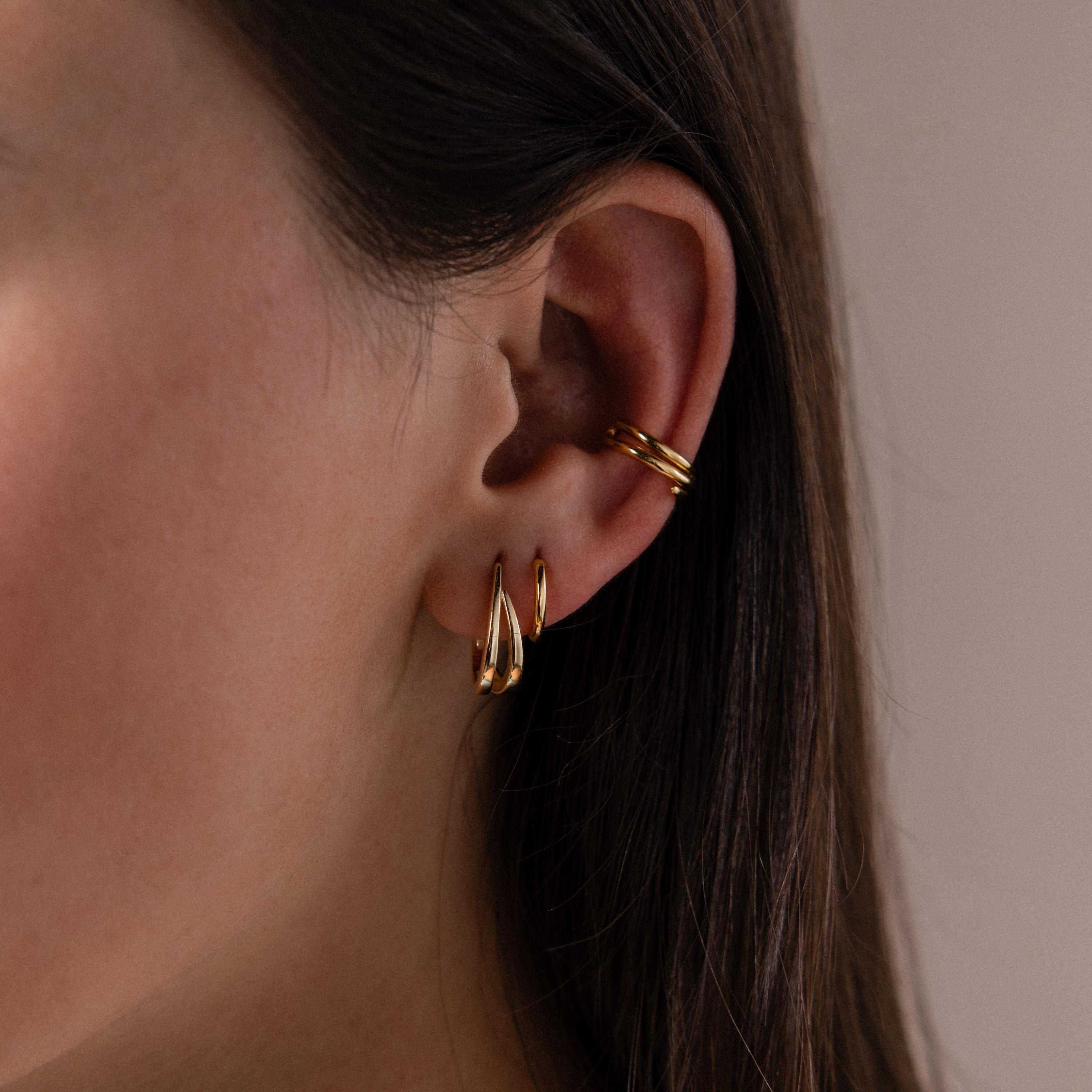 Close up of a model wearing our Oval Duo Hoops in Gold, styled with our Claw Ear Cuffs