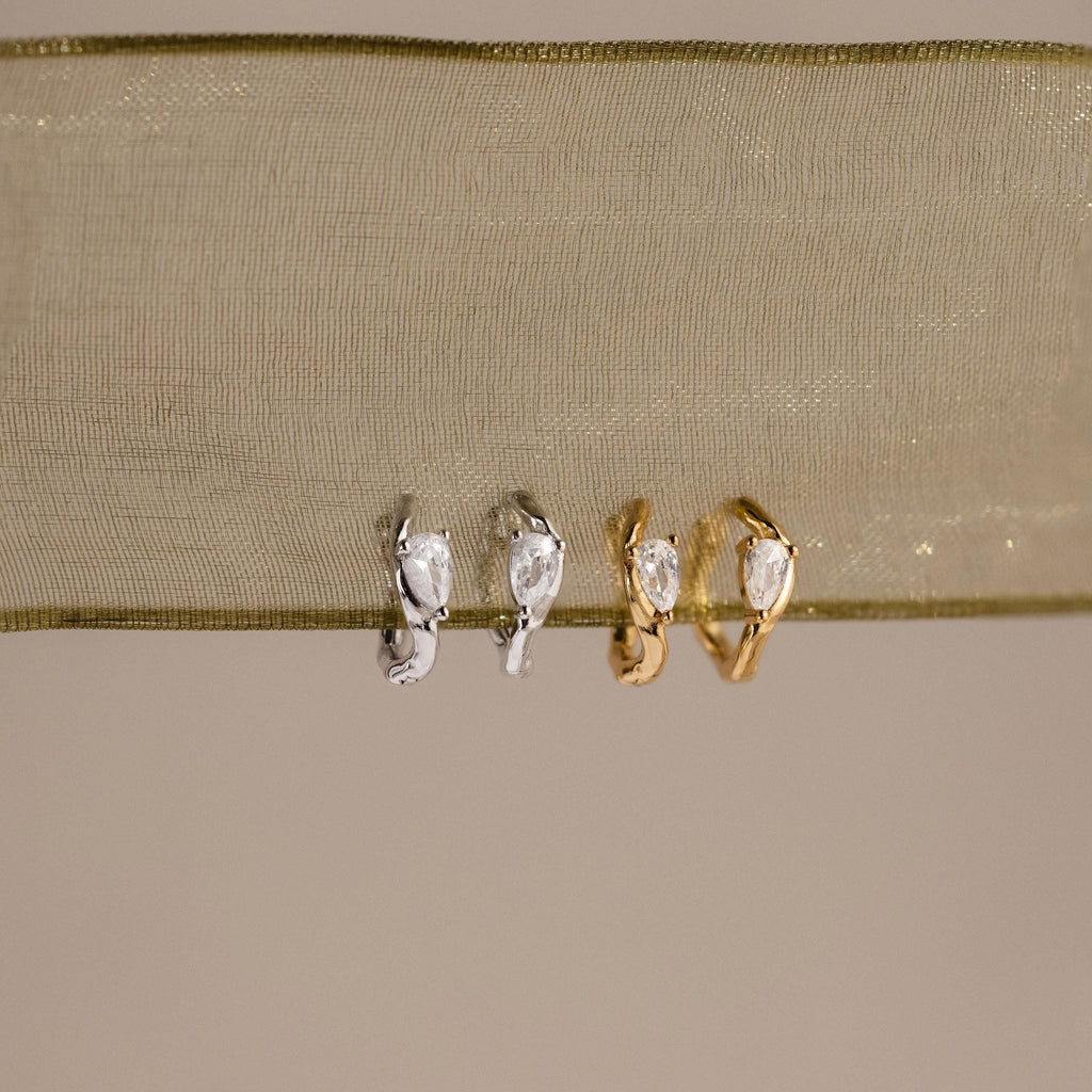 Flatlay of 2 pairs of our Hammered Diamond Teardrop Hoops in Silver and Gold