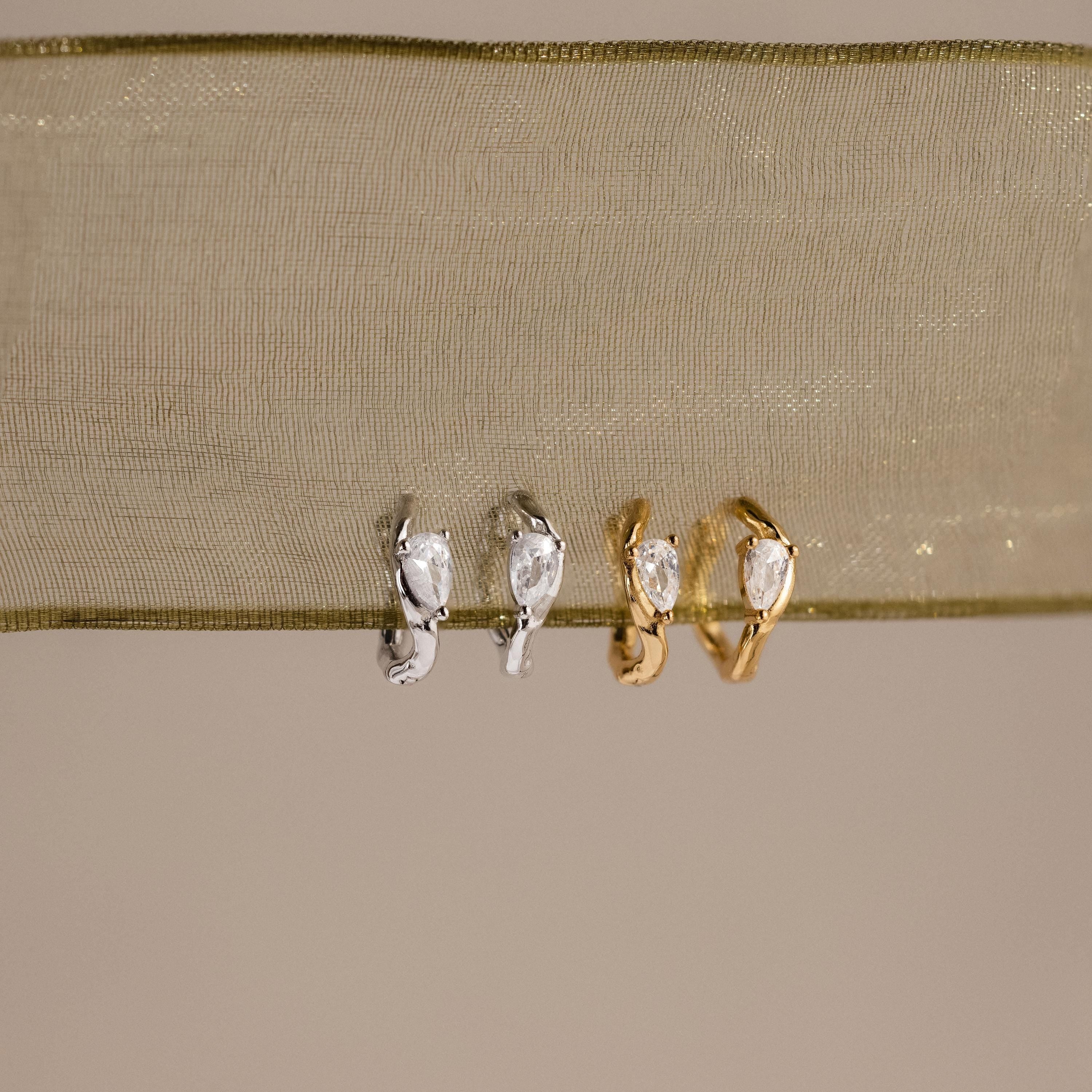 Flatlay of 2 pairs of our Hammered Diamond Teardrop Hoops in Silver and Gold