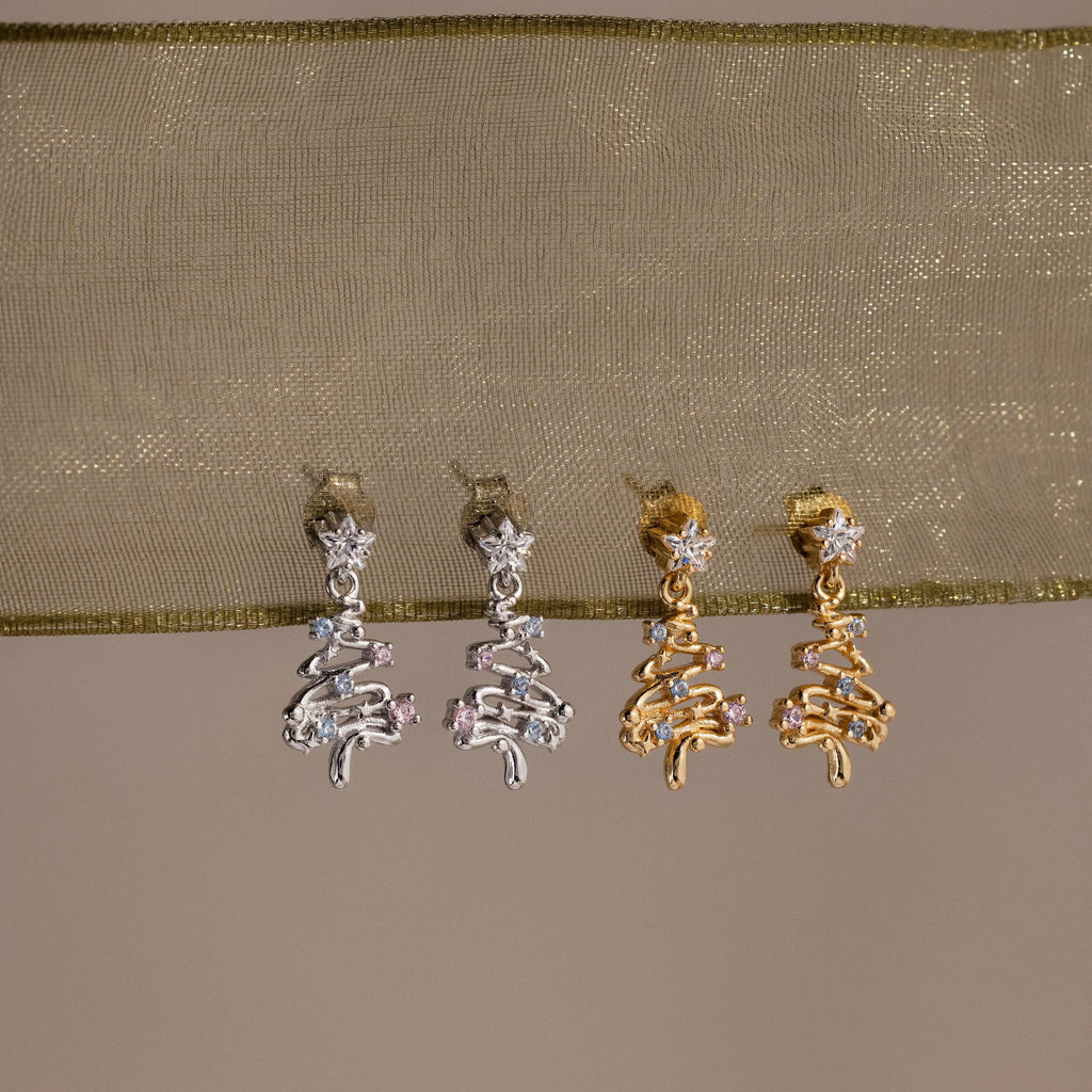Pair of silver and gold earrings on a beige fabric background