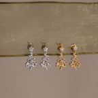 Pair of silver and gold earrings on a beige fabric background