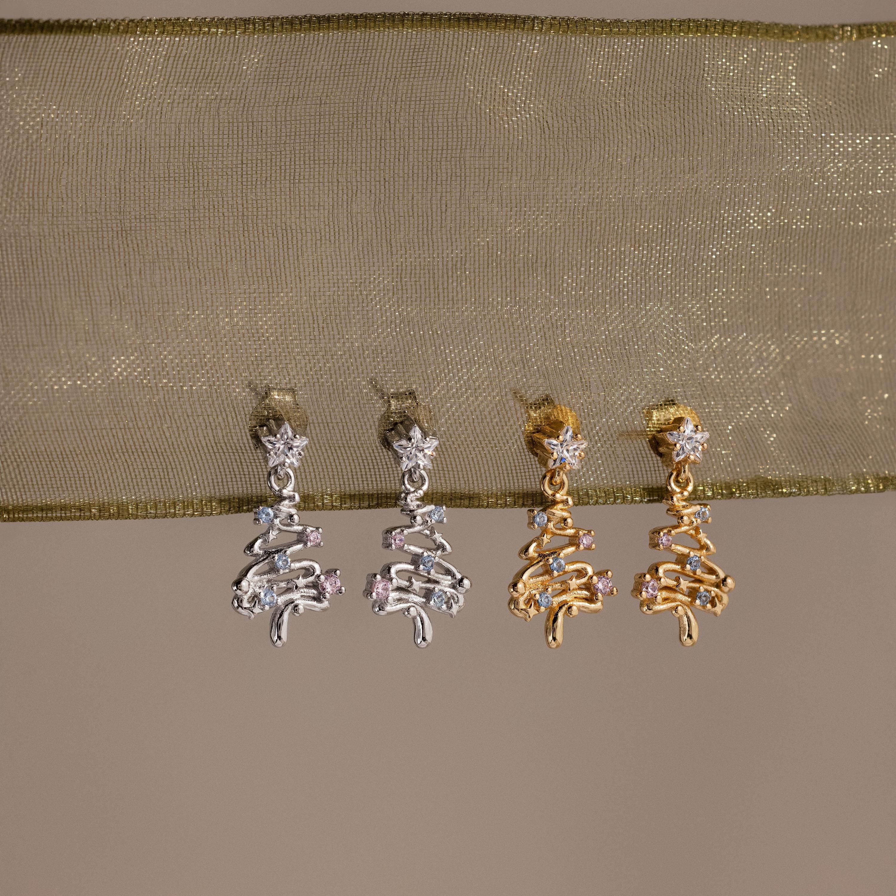 Pair of silver and gold earrings on a beige fabric background