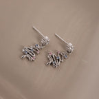 Silver Christmas tree earrings with Pink & Aquamarine gemstones on a beige surface