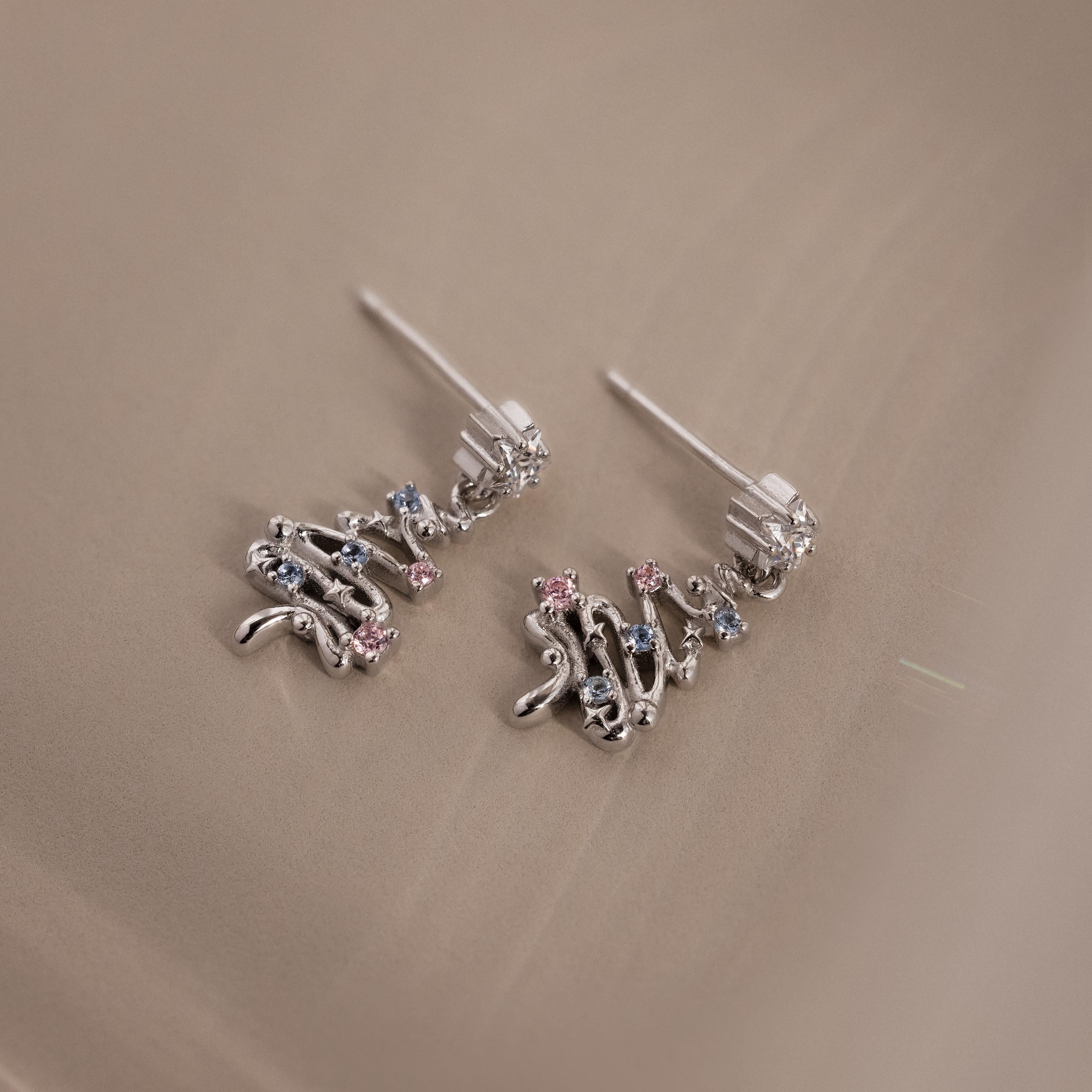 Silver Christmas tree earrings with Pink & Aquamarine gemstones on a beige surface