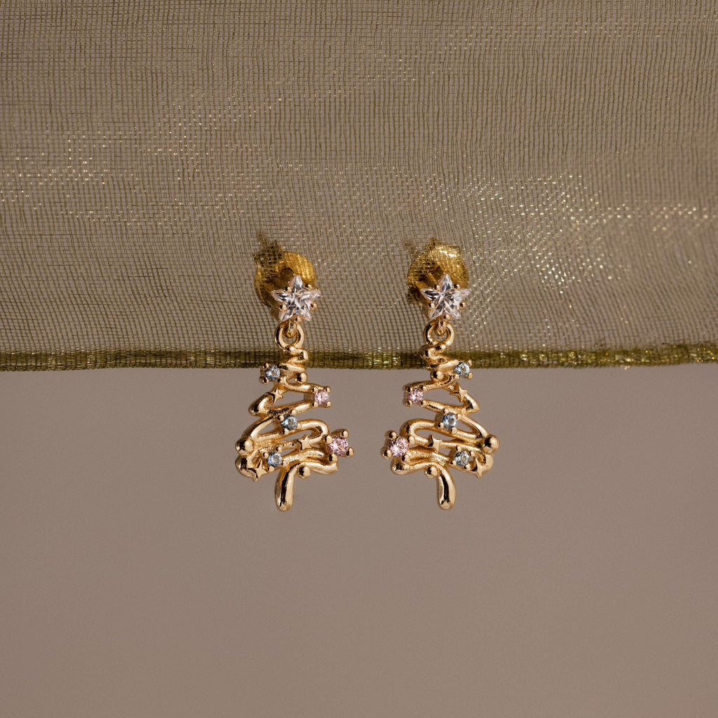 Gold Christmas tree earrings with Pink and Aquamarine gemstones on a beige fabric background