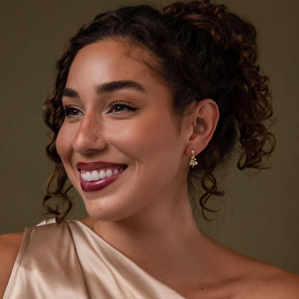 Model wearing our Holiday Tree Studs earrings against a green background