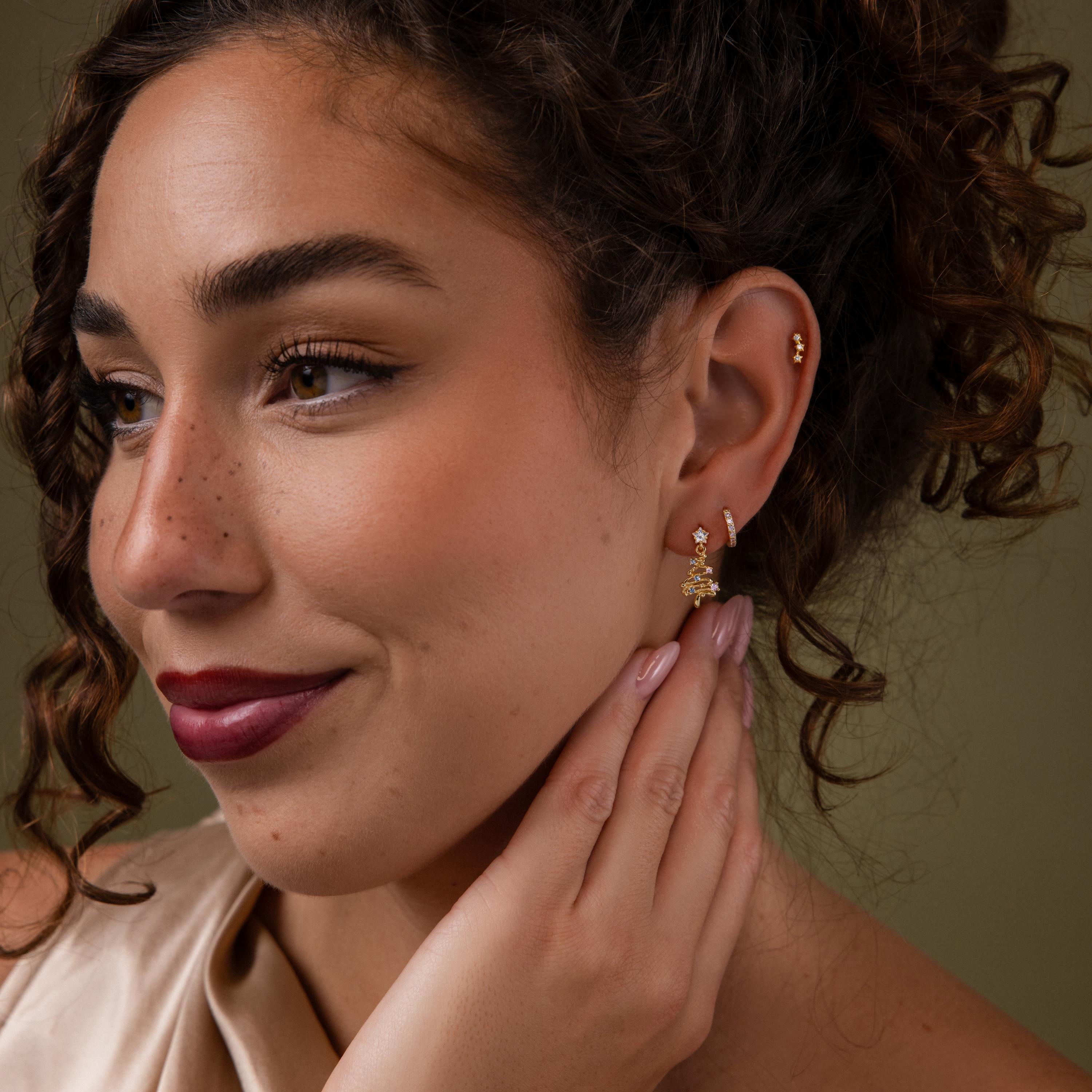 Model wearing our Holiday Diamond Tree Studs in Gold, styled with our Coco Huggies and Celestial Star Studs