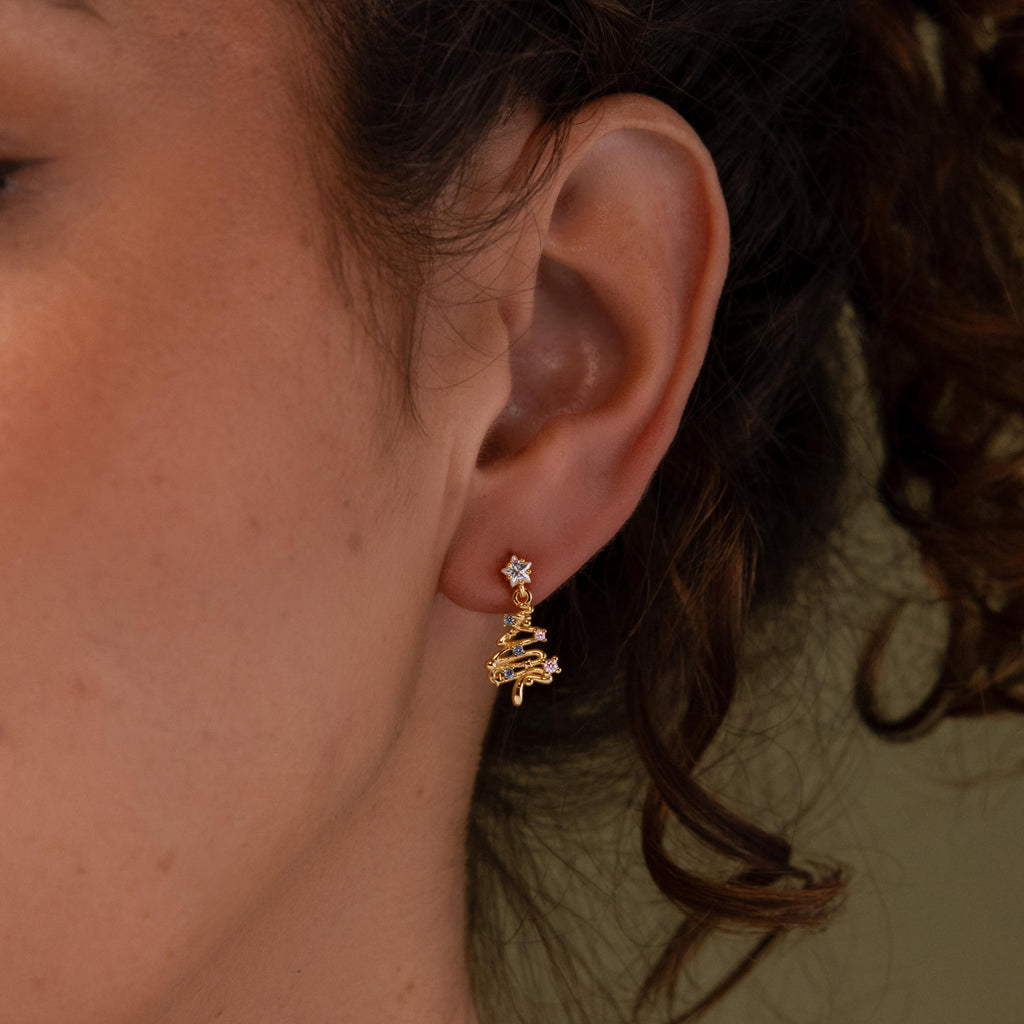 Close-up of a model wearing our Holiday Tree Studs gold earring with gemstones