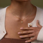 Model wearing our Diamond Poinsettia Necklace, hand resting on chest.