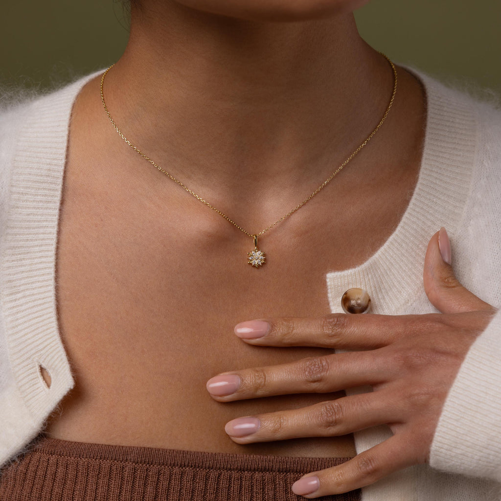 Model wearing our Diamond Poinsetta Pendant Necklace, hand resting on chest.