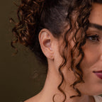 Close-up of a model wearing our Bubble Initial Flatback Studs in Gold