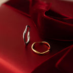 Flatlay of our Mixed Metal Wave Ring Set on a red background