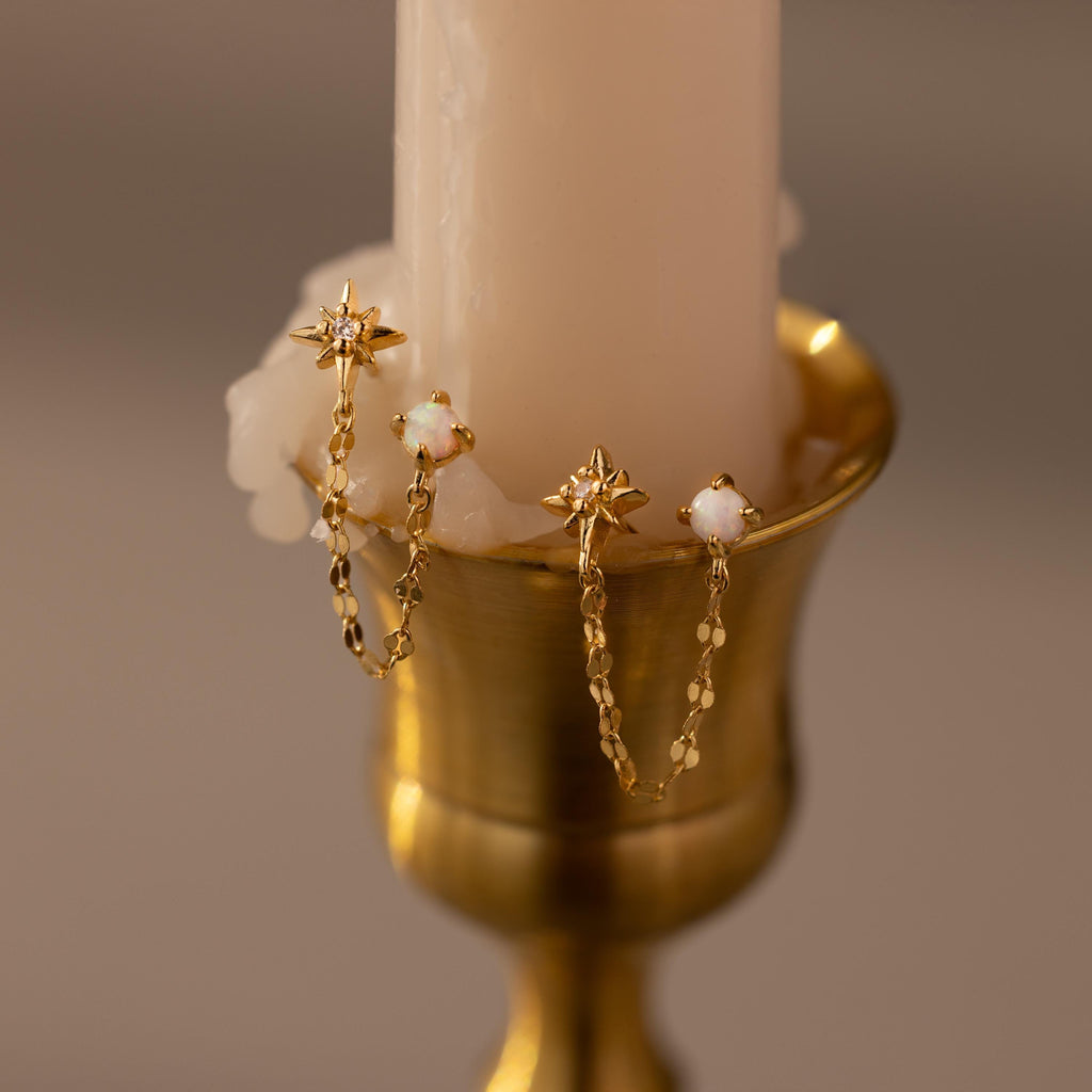 Close up of our Opal & Star Duo Chain Studs against a beige candle
